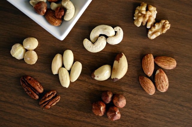 Rôzne druhy orechov poukladané na hnedom drevenom stole